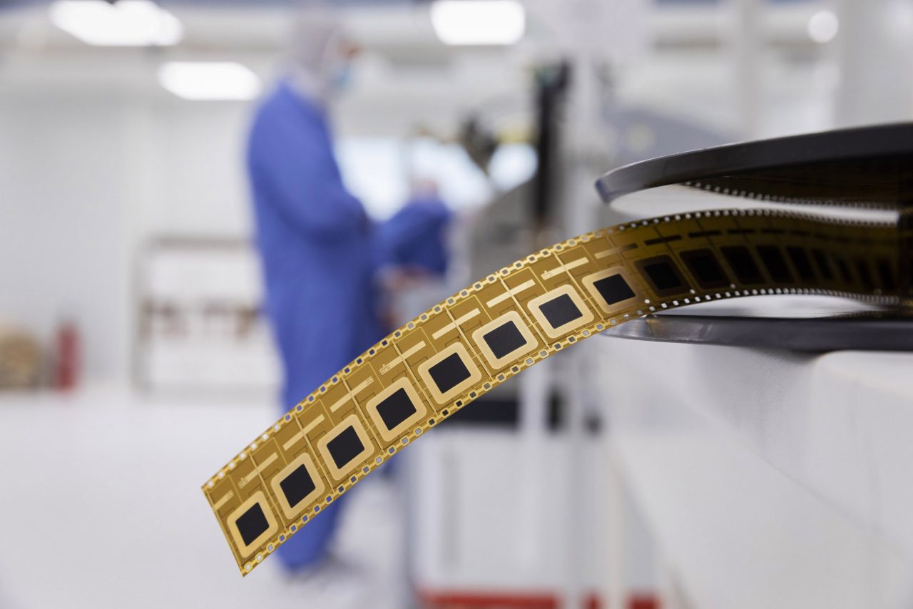 Homme au travail sur une machine de fabrication de microconnecteurs dans une salle blanche d'une entreprise industrielle