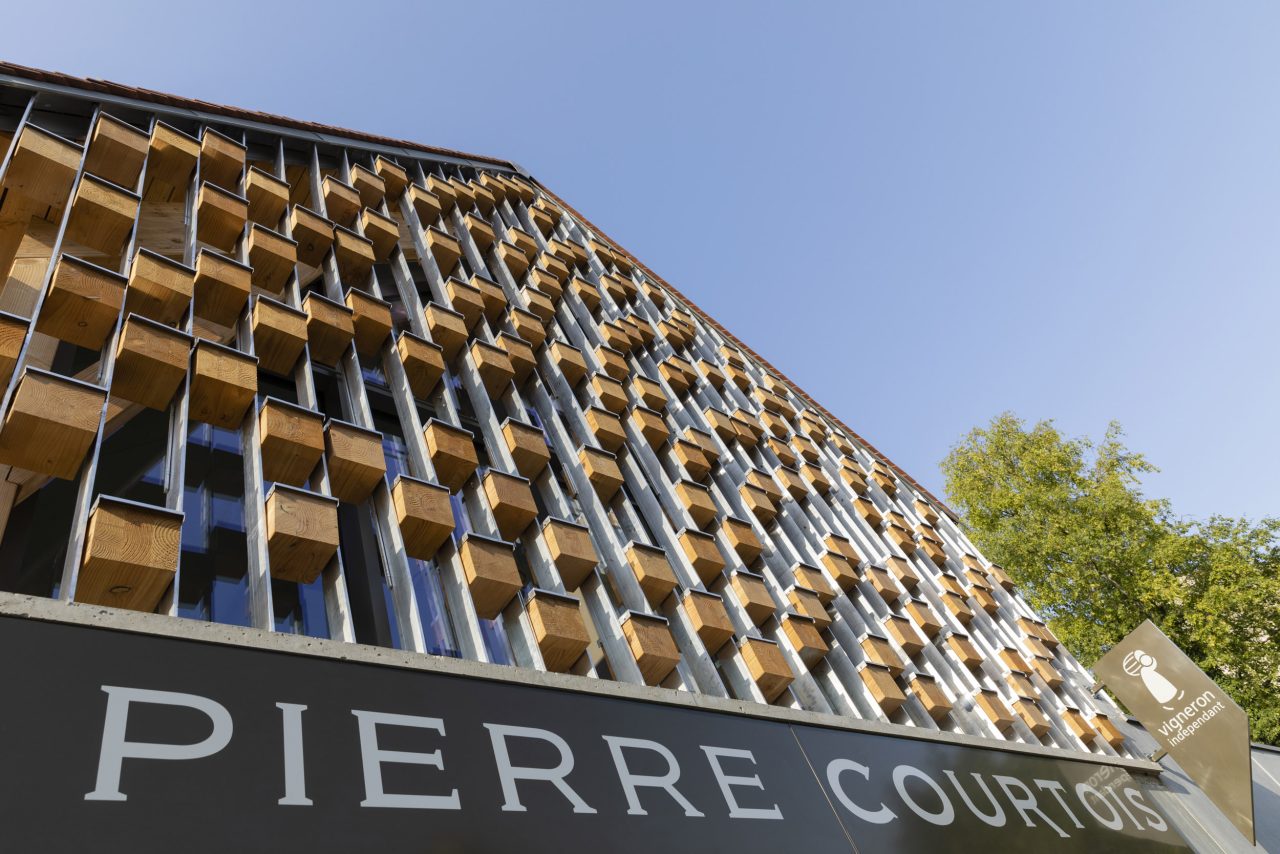 Photographie d'architecture en contre-plongée d'une façade en bois et métal sur fond de ciel bleu