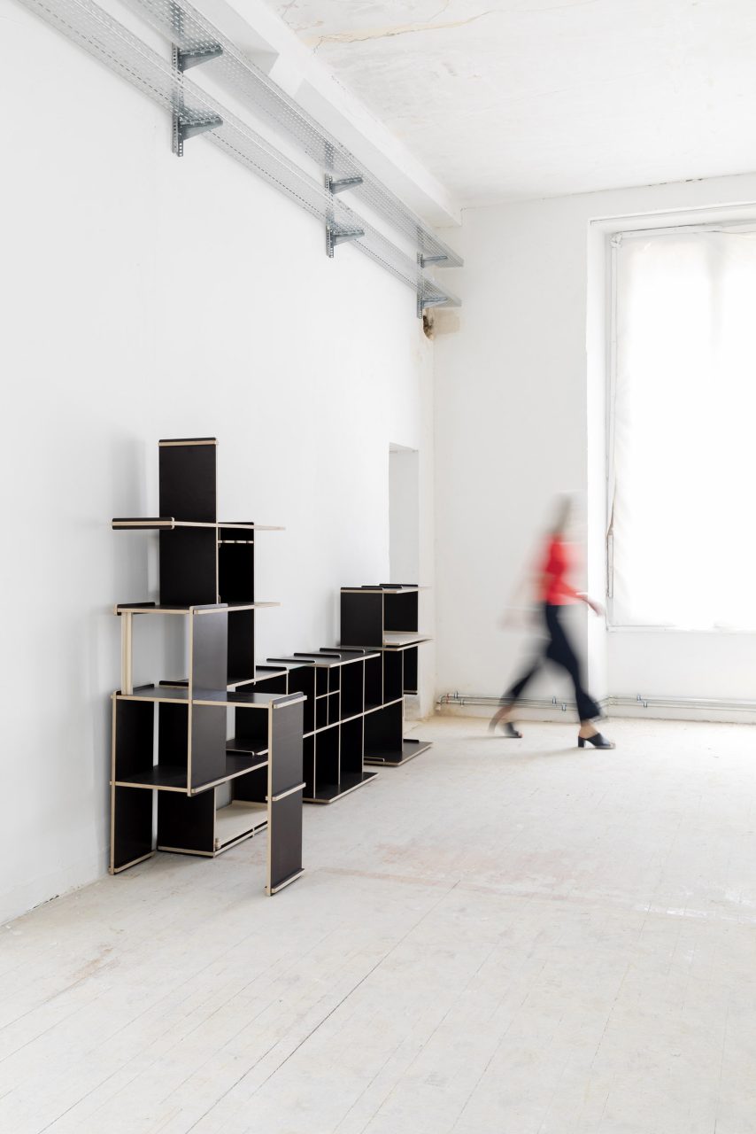 Bibliothèque modulable design réalisée en bois de coffrage par l'architecte designer Philippe Fabre, une femme est en mouvement à l'arrière plan